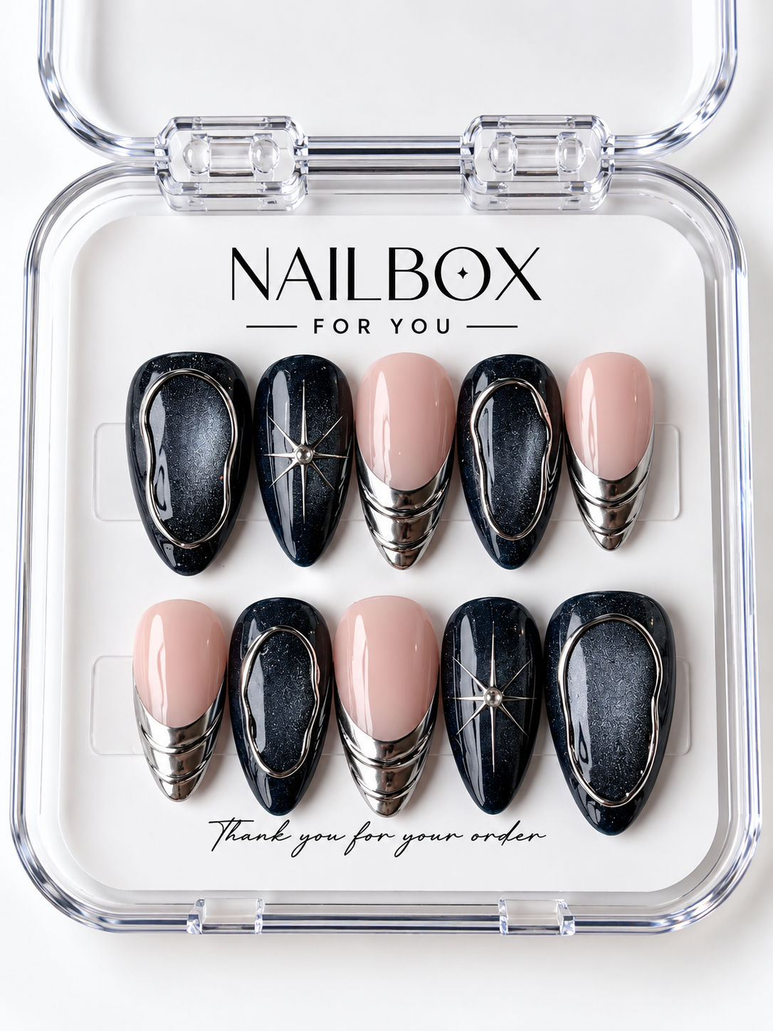 Midnight Orbit black and blush pink press-on nails with charcoal shimmer, silver-tone oval outlines, starbursts, and layered metallic French tips in a clear nail box.