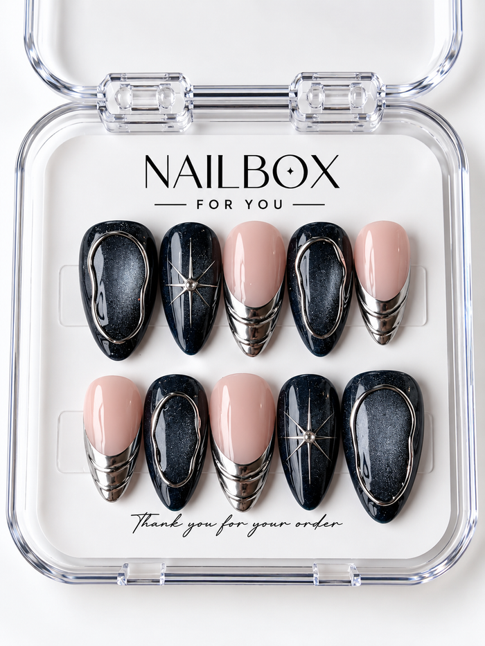 Midnight Orbit black and blush pink press-on nails with charcoal shimmer, silver-tone oval outlines, starbursts, and layered metallic French tips in a clear nail box.