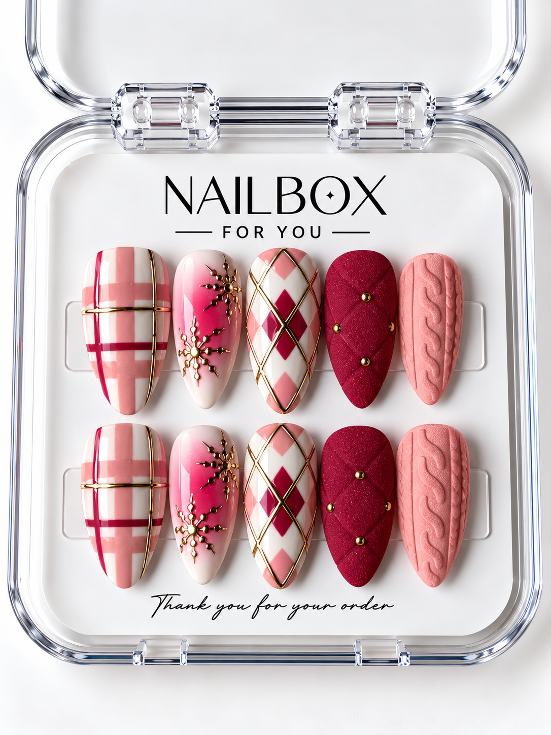 Cozy Christmas pink, berry red, and ivory press-on nails with plaid, argyle, gold-tone snowflakes, quilted studs, and raised cable-knit details in a clear nail box.