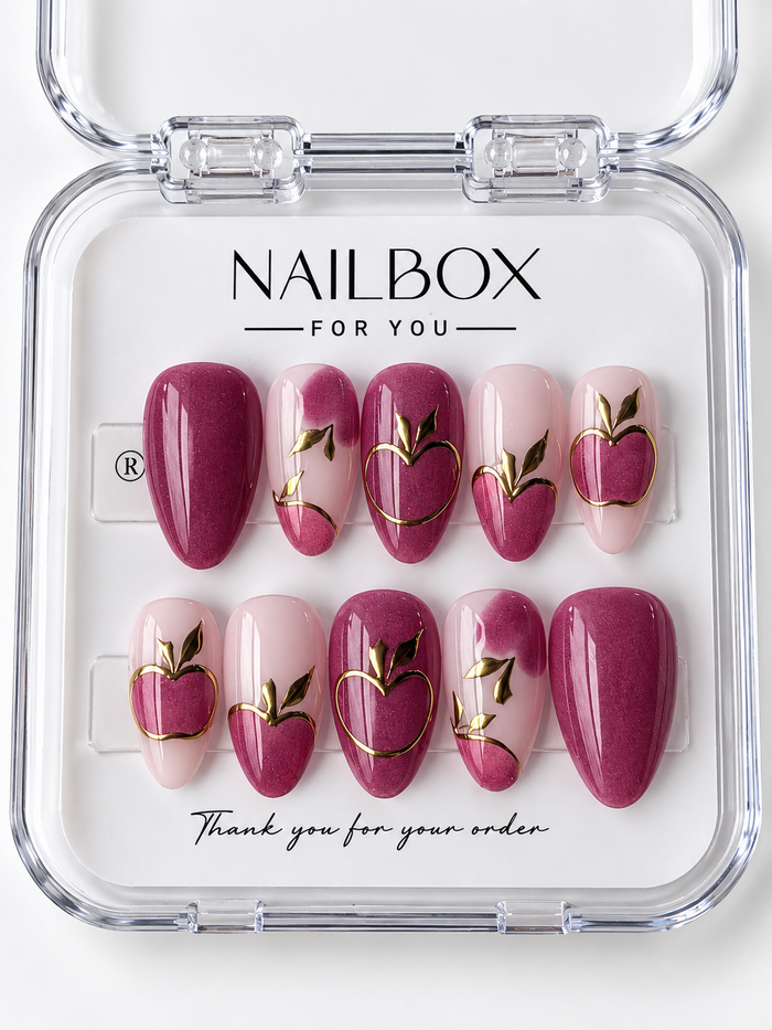 Berry Crush shimmering berry pink and blush press-on nails with apple motifs, gold-tone fruit outlines, metallic leaves, and curved accents in a clear nail box.