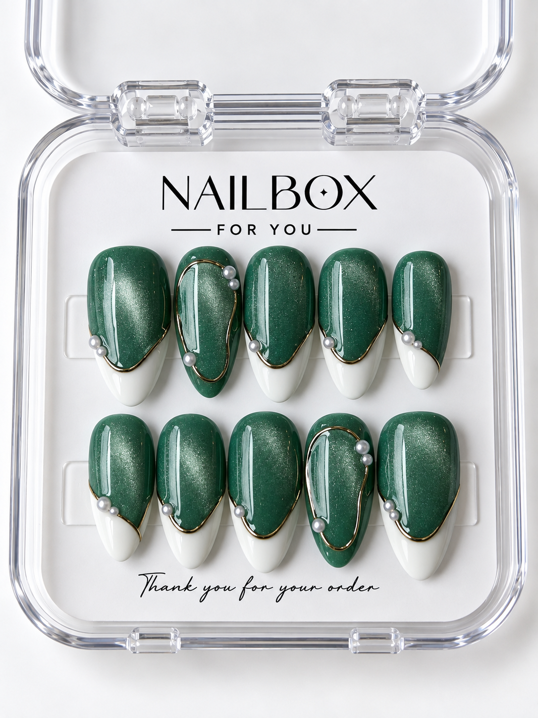Emerald Glow shimmering green press-on nails with creamy white French tips, gold-tone borders and oval outlines, and pearl-like accents in a clear nail box.