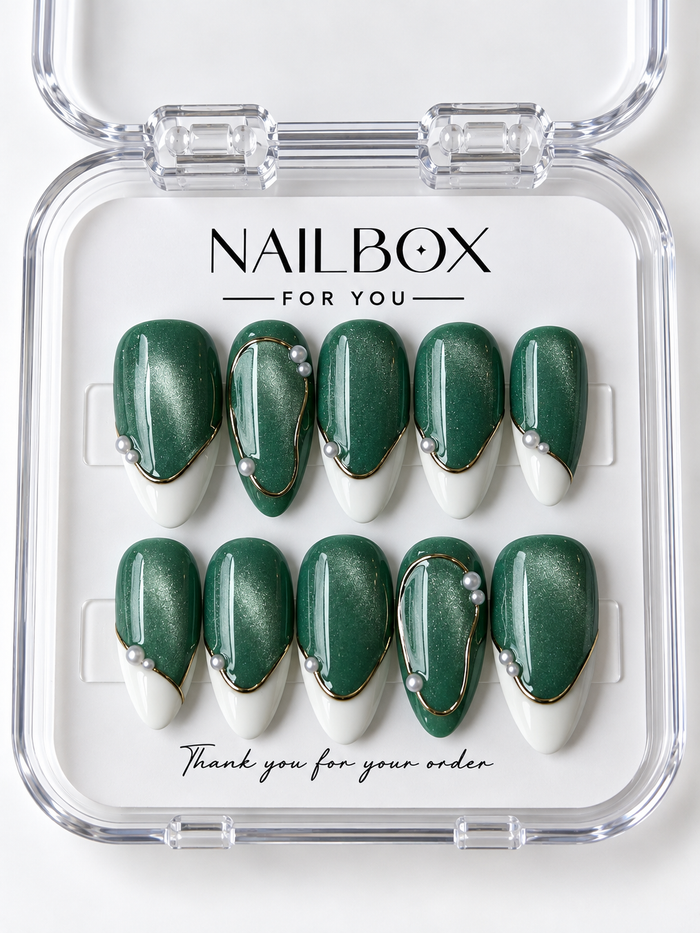 Emerald Glow shimmering green press-on nails with creamy white French tips, gold-tone borders and oval outlines, and pearl-like accents in a clear nail box.