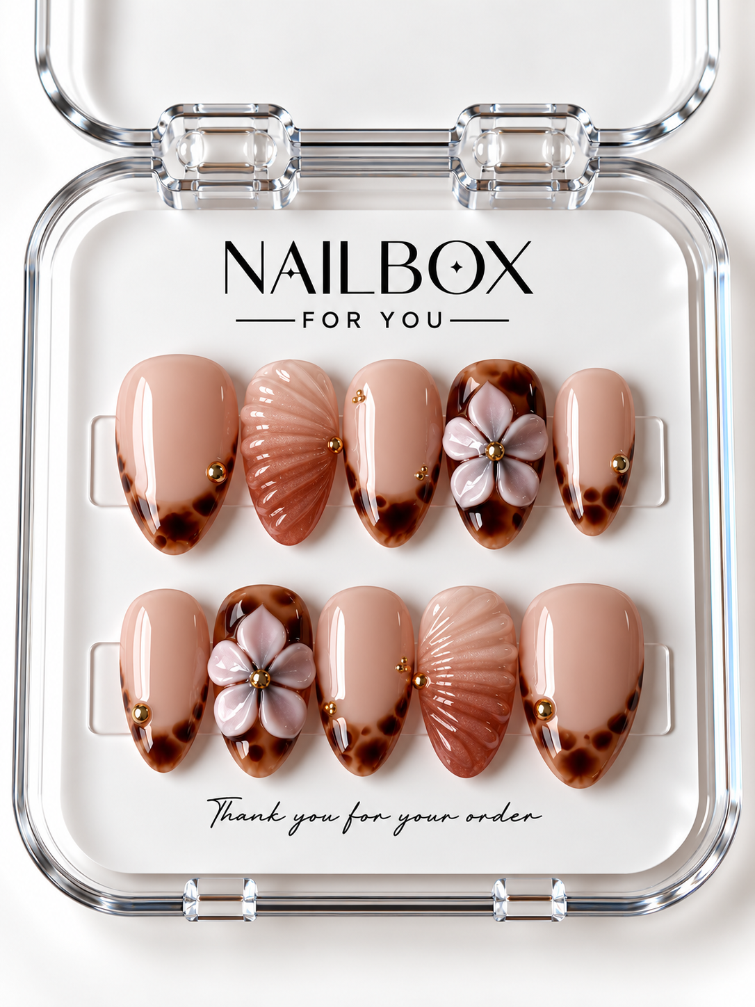 Sandy Kiss peach nude press-on nails with amber tortoiseshell tips, raised blush flowers, shimmering shell-inspired ridges, and gold-tone studs in a clear nail box.