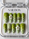 Mocha Muse green ombré press-on nails with black polka dots, raised white flowers, white lace patterns and gold bands.