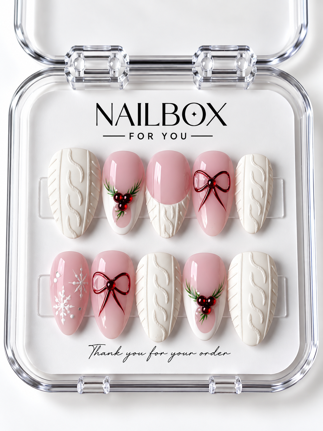 Pink Wonderland pink and ivory press-on nails with raised cable-knit patterns, burgundy bows, white snowflakes, and red berry sprigs in a clear nail box.