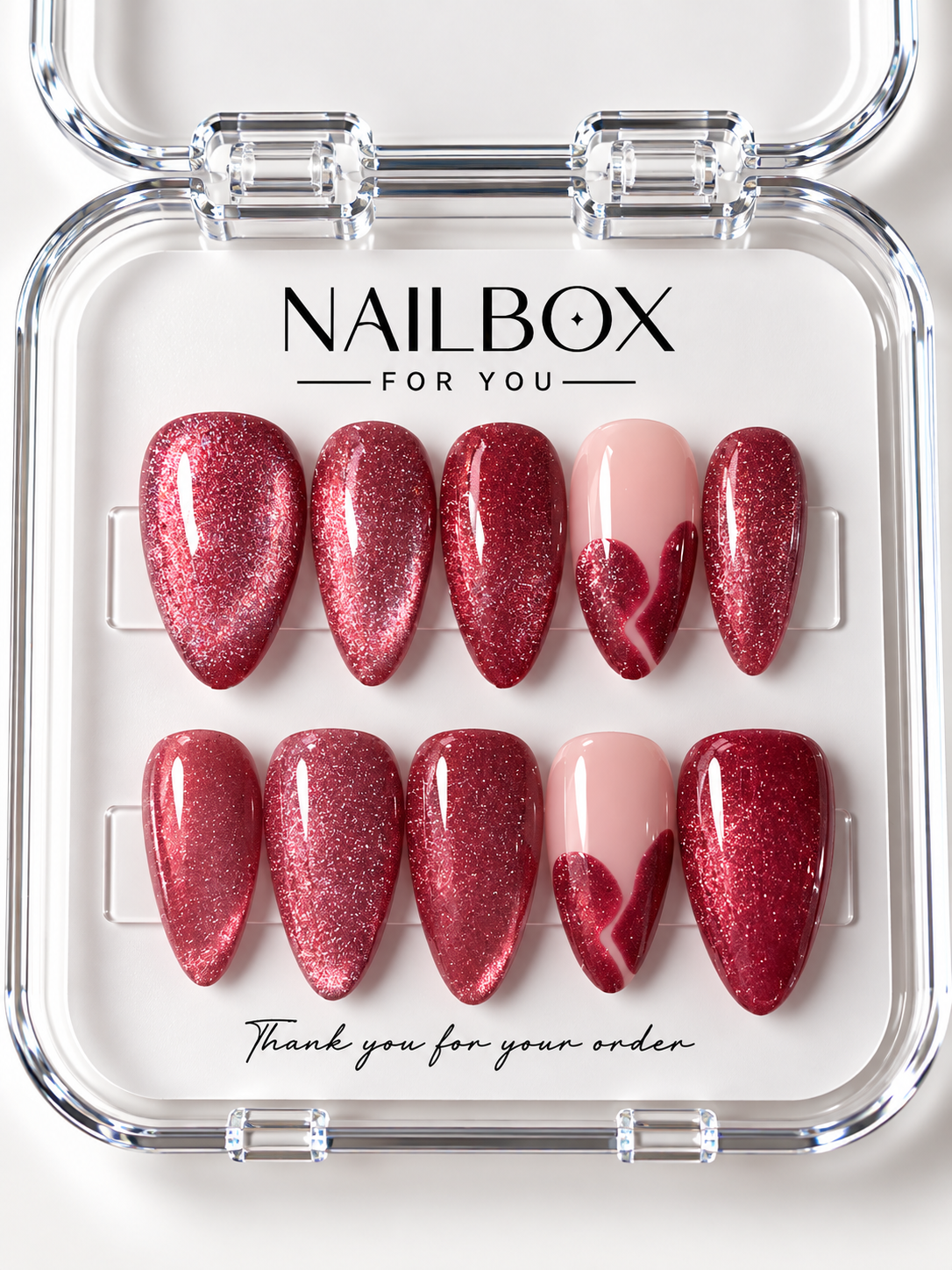 Ruby Crush ruby-red shimmer press-on nails with blush pink accent nails and glittering heart-inspired French tips, displayed in a clear nail box.