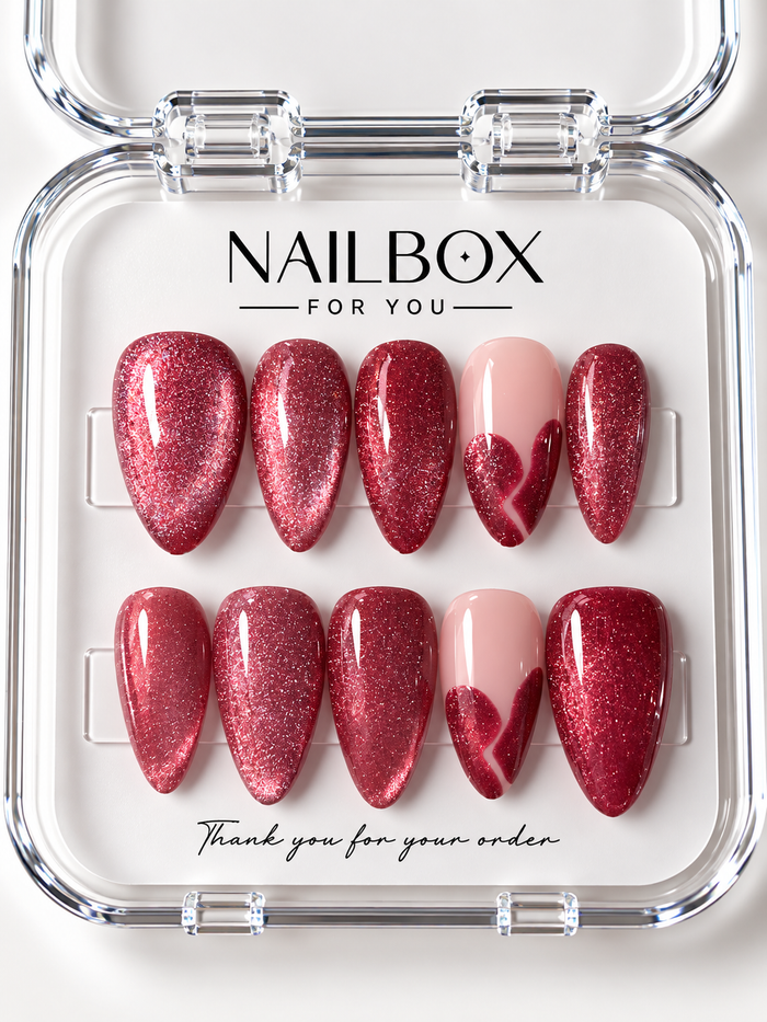 Ruby Crush ruby-red shimmer press-on nails with blush pink accent nails and glittering heart-inspired French tips, displayed in a clear nail box.