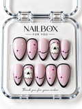 Boo in Bloom blush pink press-on nails with white ghosts, pink flowers, black outlined borders, curved French tips, and white dots in a clear nail box.