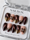 Midnight Romance burgundy cat-eye and nude pink press-on nails with gold French tips, raised flowers and sparkling gems.