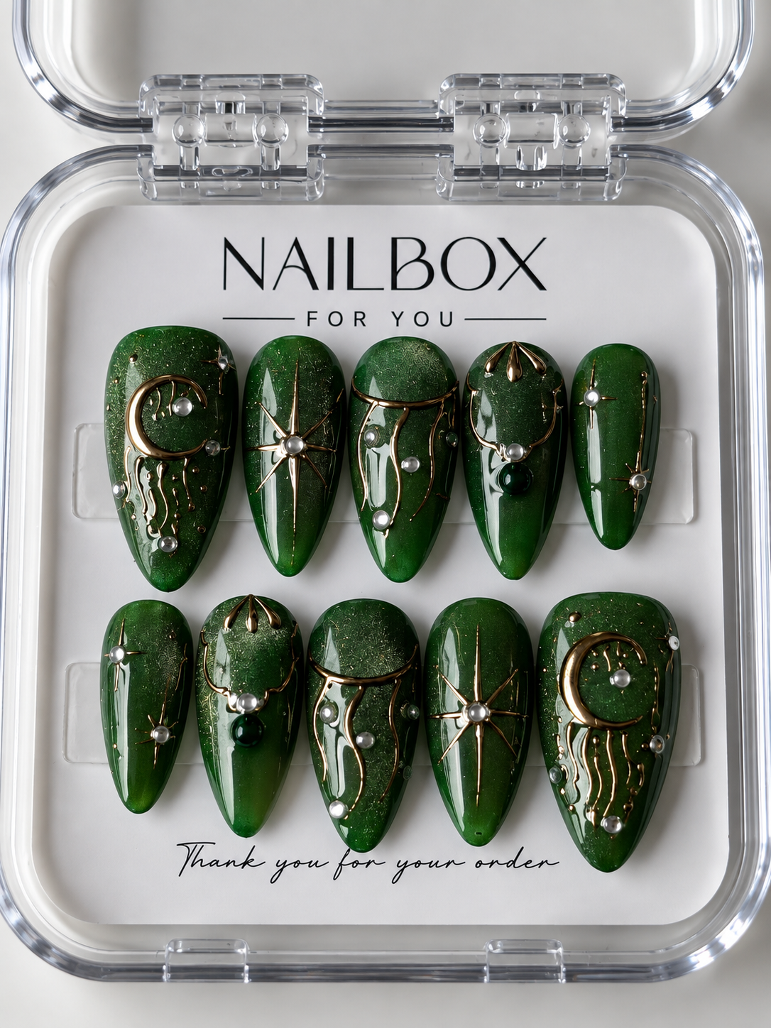Emerald Moon shimmering green press-on nails with gold crescent moons, starbursts, flowing lines and pearl-like accents.