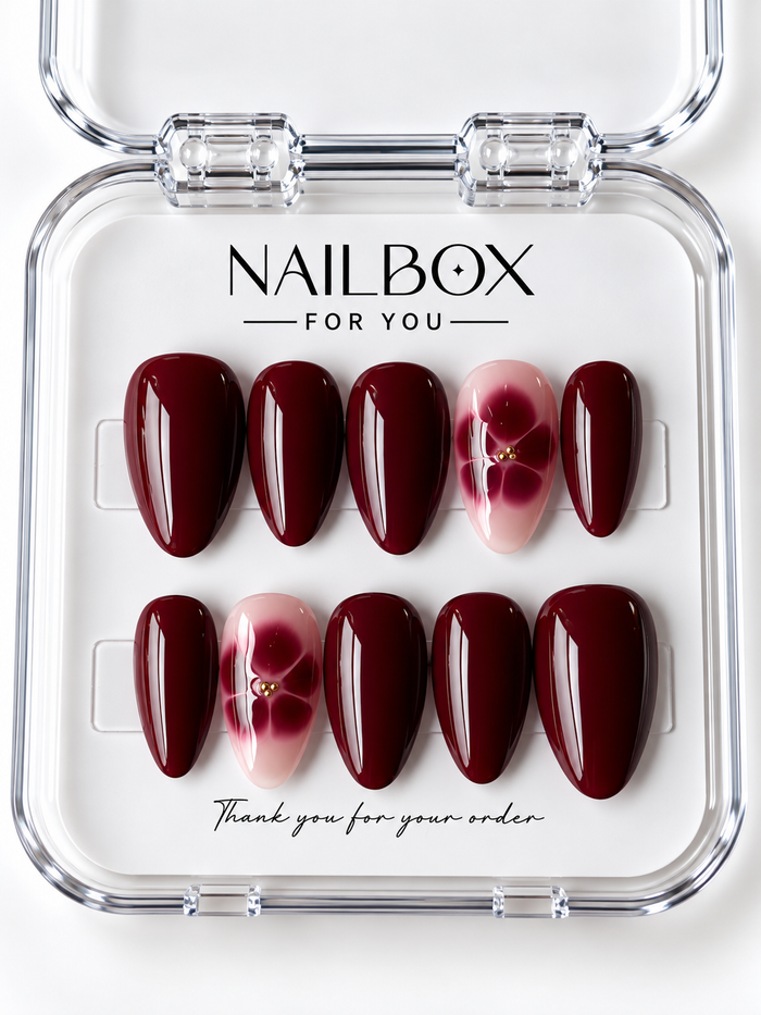 Burgundy Bloom glossy wine-red press-on nails with blush pink accent nails featuring burgundy flowers and tiny gold-tone centers, displayed in a clear nail box.
