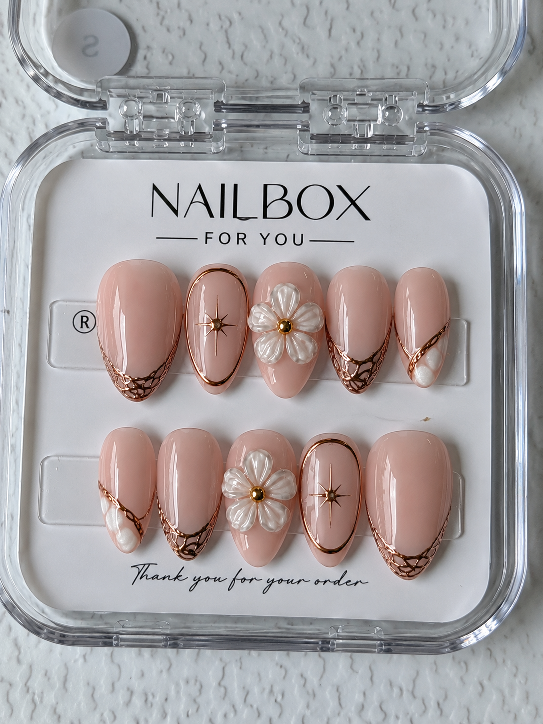Golden Petals nude pink press-on nails with raised pearlescent white flowers, rose gold lattice tips and starburst accents.
