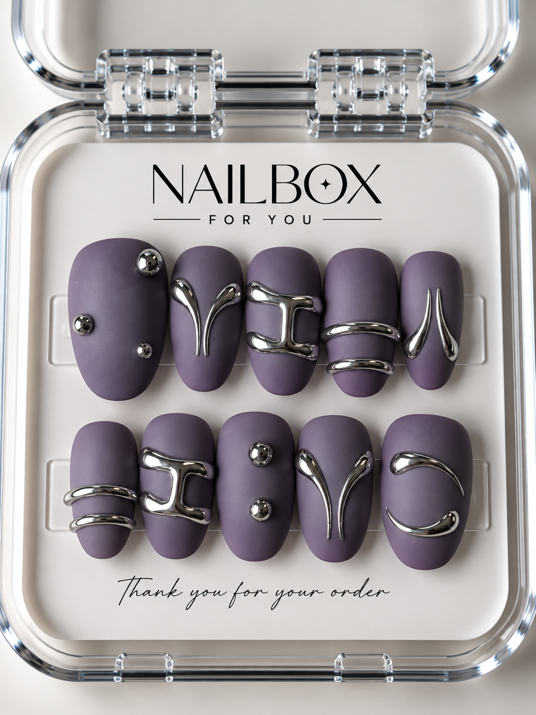 Lilac Rebel matte purple press-on nails with raised silver curves, double bands and round studs, displayed in a clear nail box.