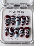 Cherry Swirl glossy deep cherry red press-on nails with pastel blue looping swirls, curved bands and abstract waves.