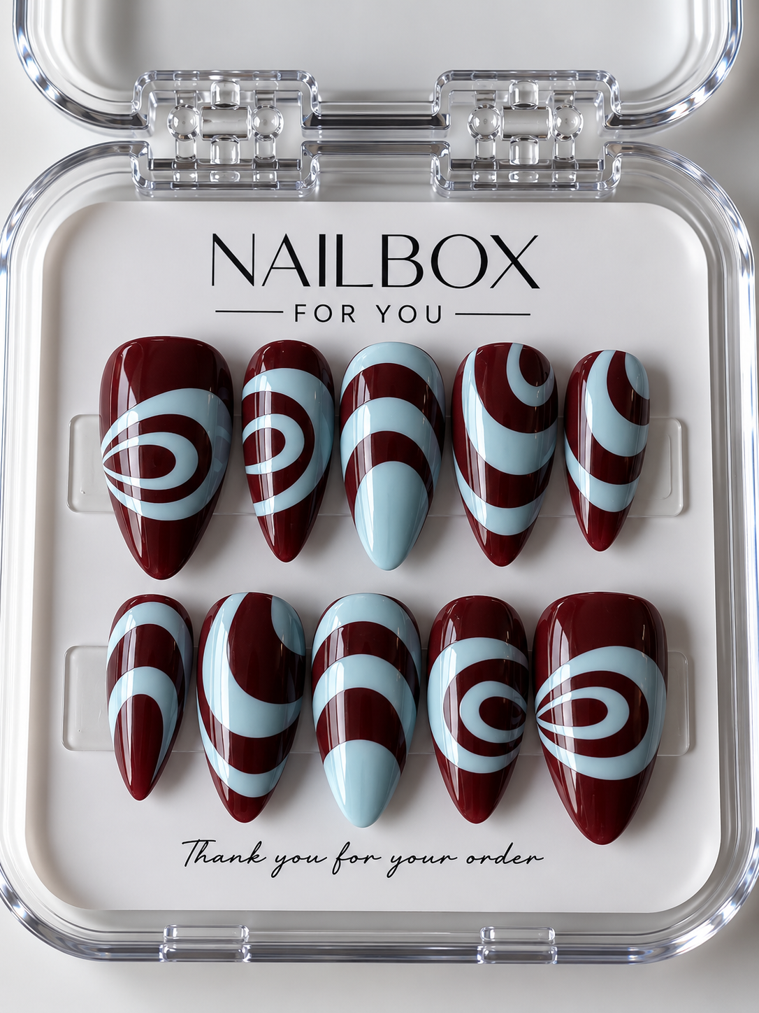 Cherry Swirl glossy deep cherry red press-on nails with pastel blue looping swirls, curved bands and abstract waves.