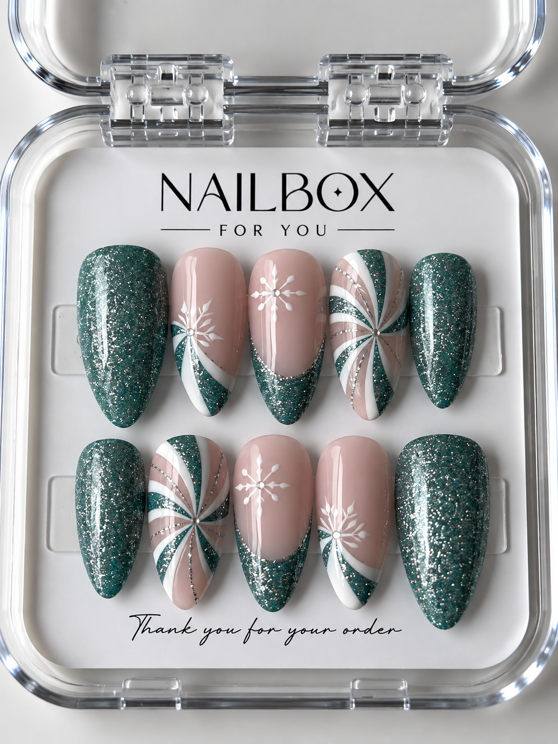 Frosted Evergreen green glitter and nude pink press-on nails with white snowflakes, swirling patterns and silver accents.