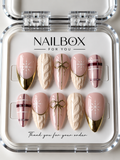 Winter Romance blush pink press-on nails with white snowflakes, cream knit textures, burgundy plaid and gold bows.